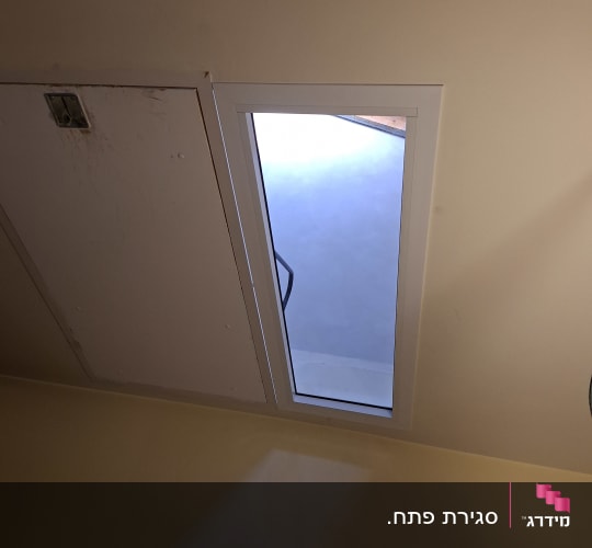 חלון אלומיניום בודד שנפתח על ציר המותקן בחדר ממ"ד